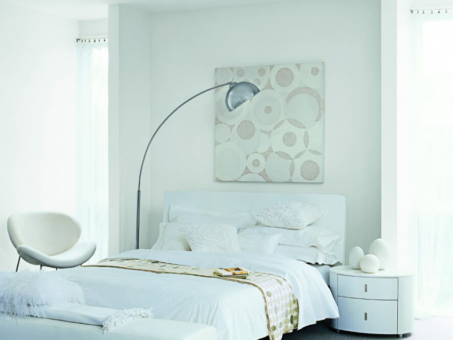Clean White Bedroom with White Bed Covers and Pillows with Chair and bedside table and lamp